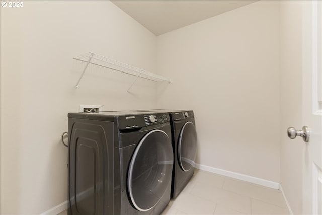 laundry area featuring laundry area, baseboards, washing machine and clothes dryer, and light tile patterned floors