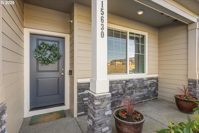 property entrance featuring stone siding and a porch