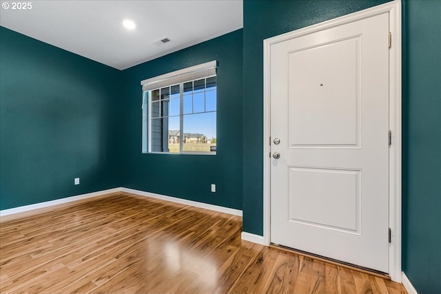 foyer with wood finished floors, visible vents, and baseboards