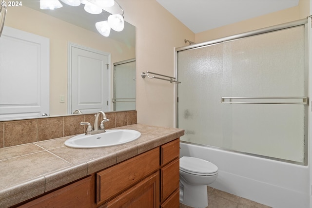 full bath featuring tile patterned flooring, toilet, vanity, and shower / bath combination with glass door