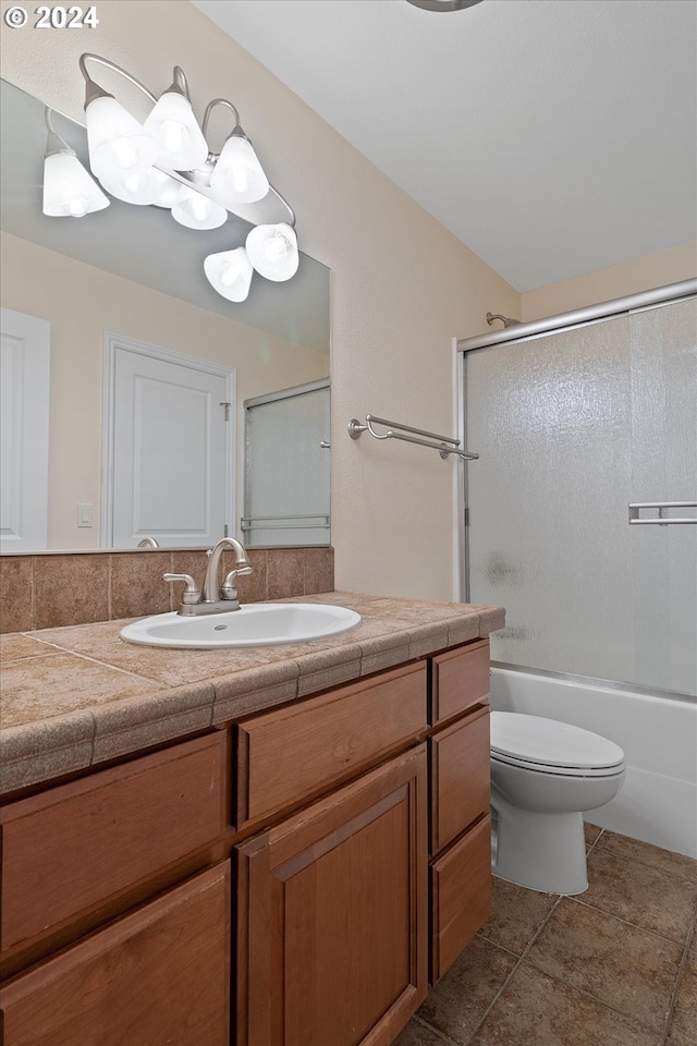 full bath featuring tile patterned flooring, toilet, vanity, and bath / shower combo with glass door