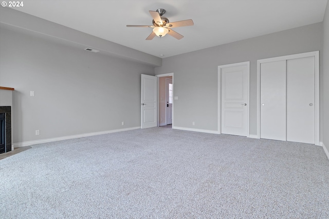 unfurnished bedroom featuring visible vents, carpet flooring, a tile fireplace, and baseboards