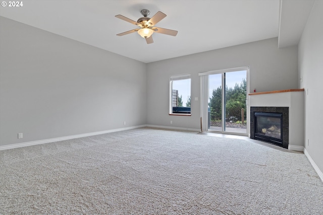 unfurnished living room featuring a fireplace, a ceiling fan, baseboards, and carpet floors