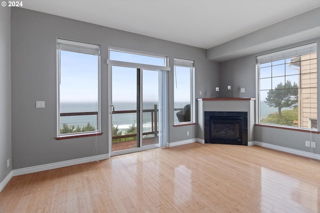 unfurnished living room featuring a glass covered fireplace, baseboards, and wood finished floors