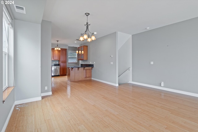 kitchen with visible vents, light wood-type flooring, a kitchen bar, dark countertops, and open floor plan