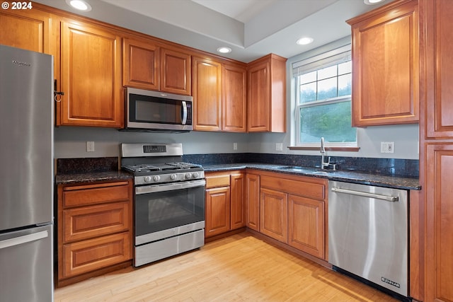 kitchen featuring recessed lighting, appliances with stainless steel finishes, light wood-style floors, brown cabinetry, and a sink