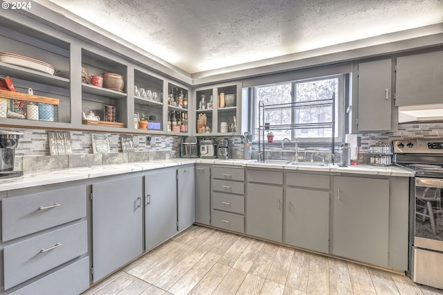 kitchen with backsplash, gray cabinets, sink, and stainless steel electric range