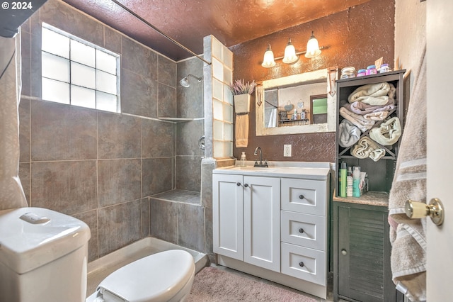 bathroom featuring toilet, vanity, and tiled shower