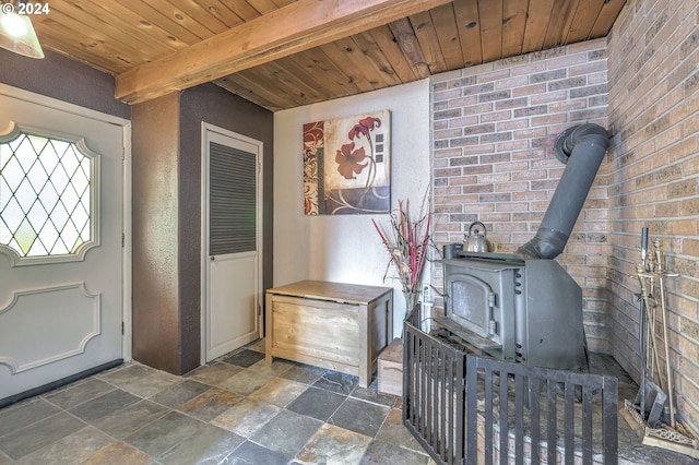 foyer with a wood stove, beamed ceiling, wooden ceiling, and brick wall