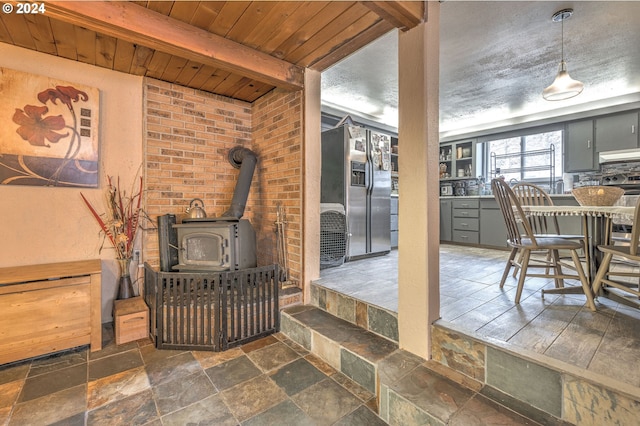 living room with a wood stove and beamed ceiling