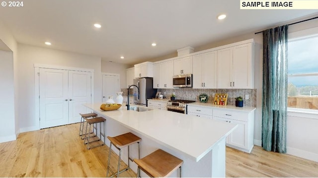 kitchen featuring a breakfast bar, white cabinetry, an island with sink, and appliances with stainless steel finishes