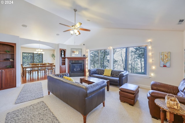 living room featuring light colored carpet, ceiling fan with notable chandelier, and high vaulted ceiling