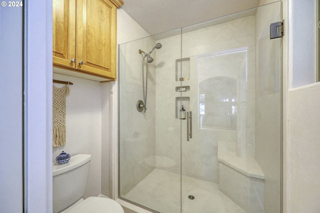 bathroom featuring a shower with shower door and toilet