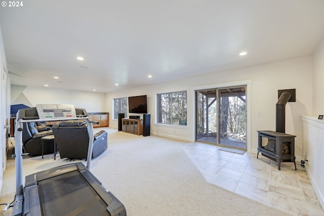 exercise room with light carpet and a wood stove