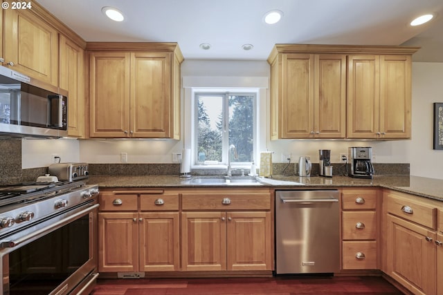 kitchen featuring dark stone countertops, sink, dark wood-type flooring, and stainless steel appliances