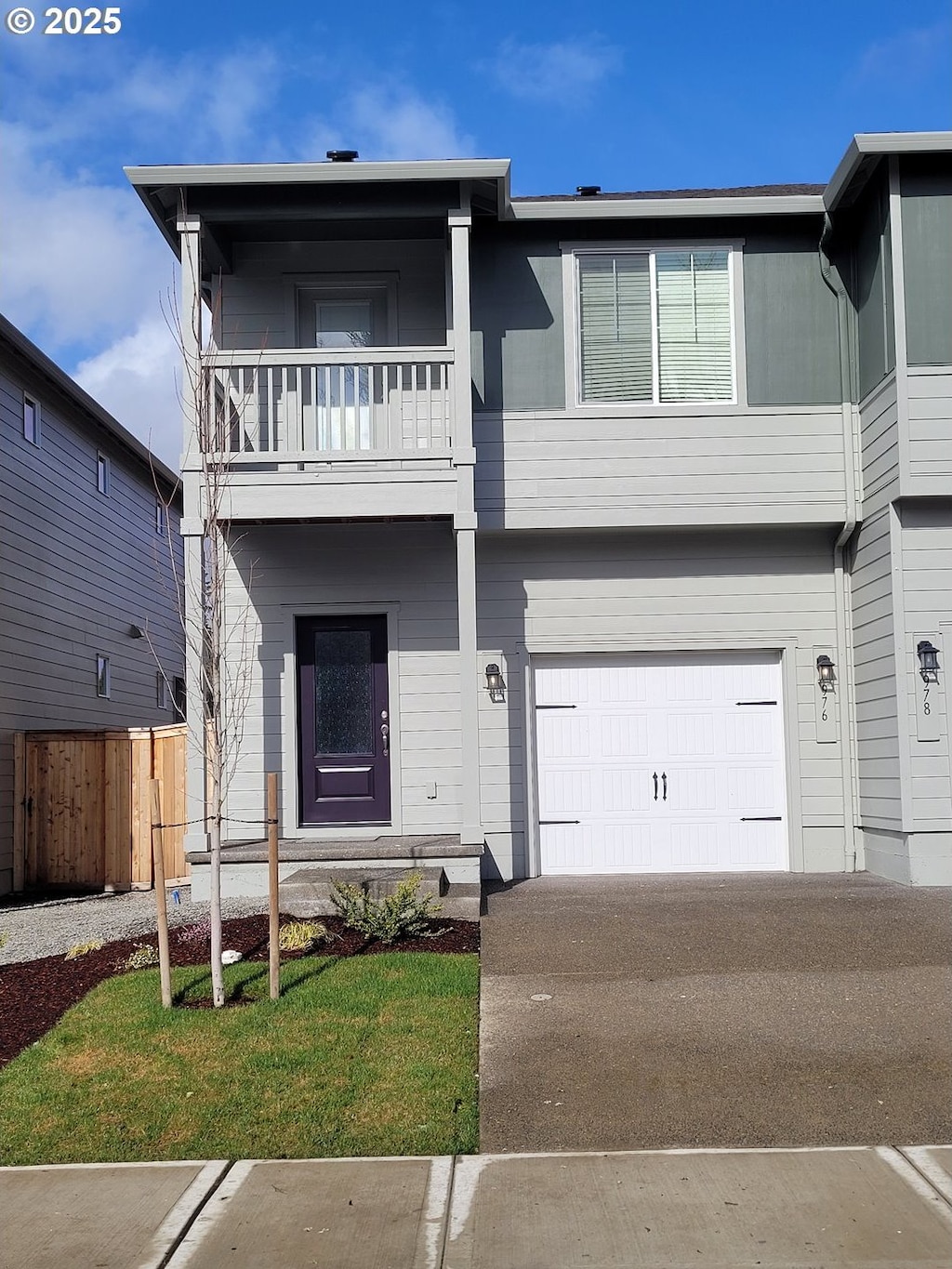 view of front facade featuring driveway, a garage, a balcony, fence, and a front lawn