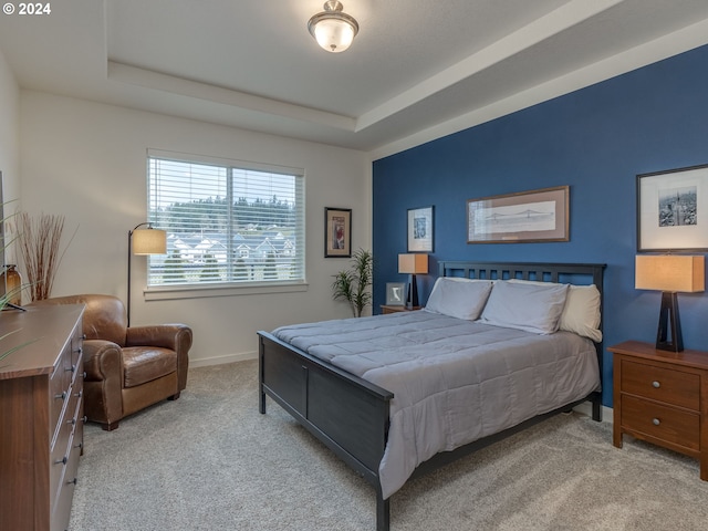 bedroom with a tray ceiling and light colored carpet