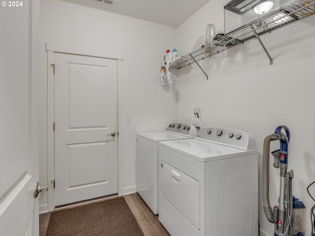 laundry room with washing machine and clothes dryer and hardwood / wood-style flooring