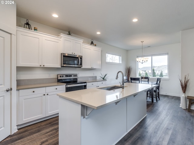 kitchen with appliances with stainless steel finishes, sink, pendant lighting, a center island with sink, and white cabinets