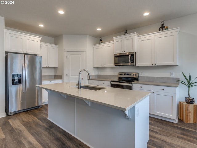 kitchen featuring white cabinets, sink, an island with sink, dark hardwood / wood-style flooring, and stainless steel appliances