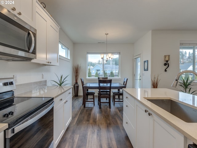 kitchen with an inviting chandelier, hanging light fixtures, sink, appliances with stainless steel finishes, and white cabinetry