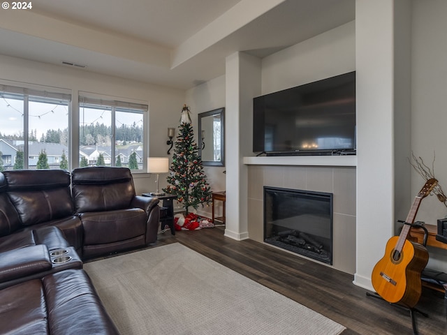 living room with a tiled fireplace and dark hardwood / wood-style floors