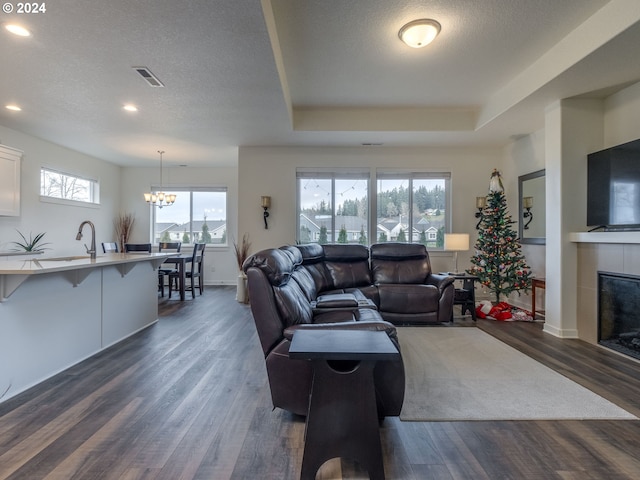 living room featuring dark hardwood / wood-style floors, a wealth of natural light, a tray ceiling, and a tiled fireplace