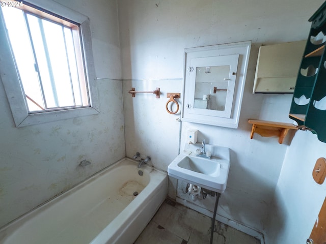 bathroom featuring a wealth of natural light, a tub, and sink