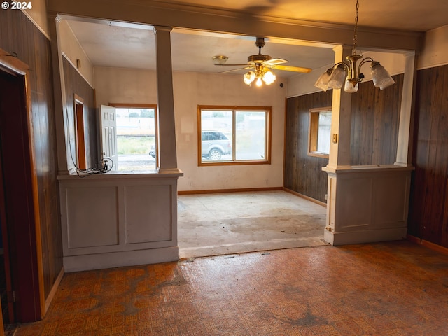 empty room with wood walls and ceiling fan with notable chandelier