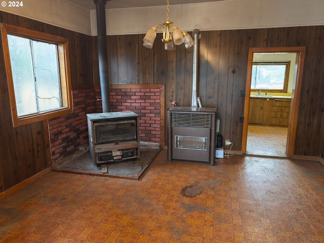 living room featuring wooden walls, heating unit, a healthy amount of sunlight, and a notable chandelier