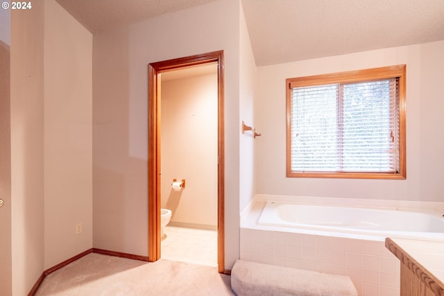 bathroom featuring a relaxing tiled tub, a textured ceiling, and toilet