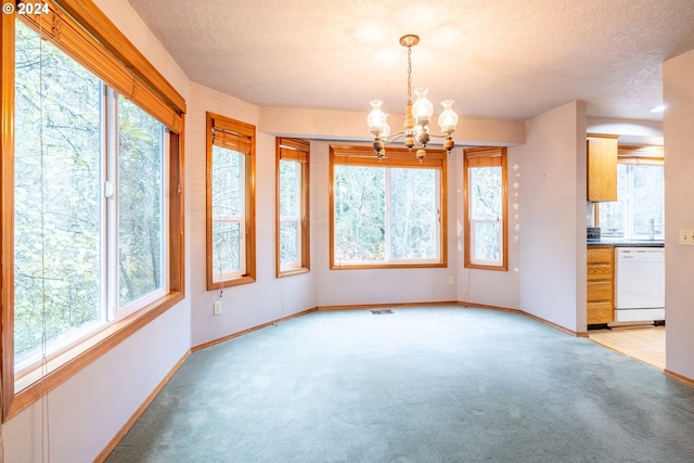 unfurnished dining area with a textured ceiling, plenty of natural light, and a notable chandelier