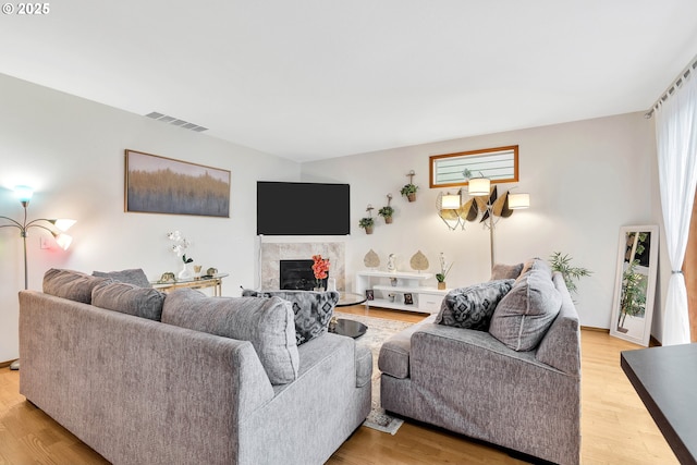 living room featuring a tile fireplace and light hardwood / wood-style flooring