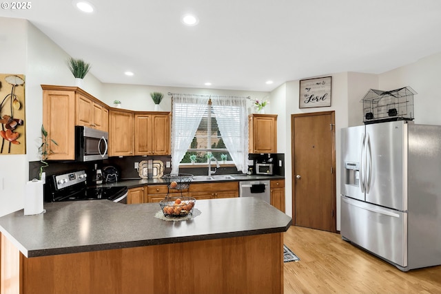 kitchen with appliances with stainless steel finishes, light wood-type flooring, kitchen peninsula, sink, and tasteful backsplash