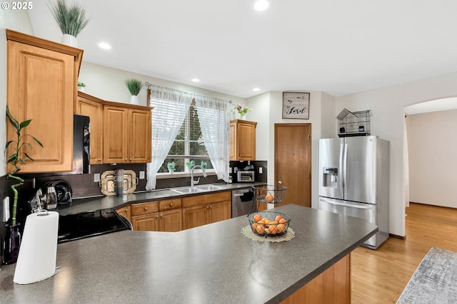 kitchen featuring stainless steel appliances, light hardwood / wood-style floors, sink, and backsplash