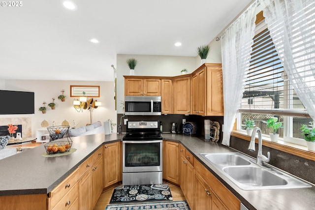 kitchen featuring sink, stainless steel appliances, light wood-type flooring, and kitchen peninsula