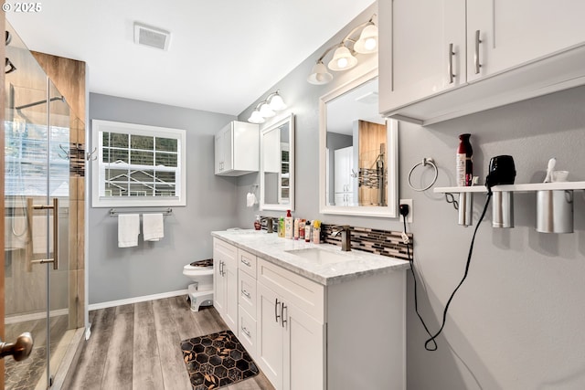 bathroom featuring toilet, wood-type flooring, walk in shower, backsplash, and vanity