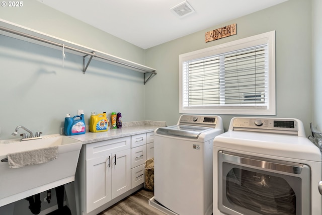 laundry room featuring sink, independent washer and dryer, cabinets, and dark hardwood / wood-style floors