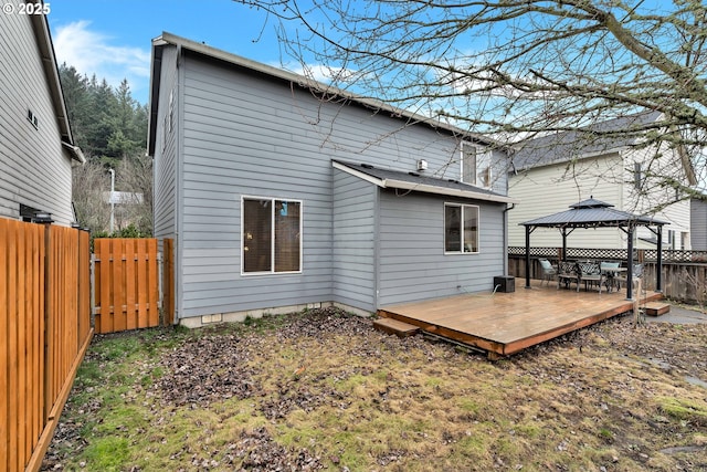 back of property featuring a deck and a gazebo