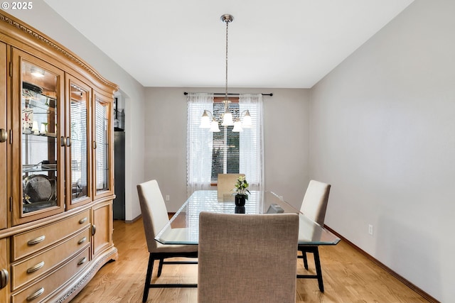 dining area featuring light wood-type flooring and a notable chandelier