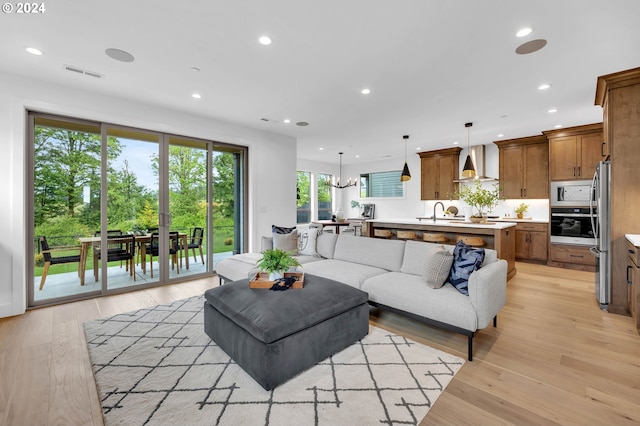 living room with sink, a chandelier, and light wood-type flooring