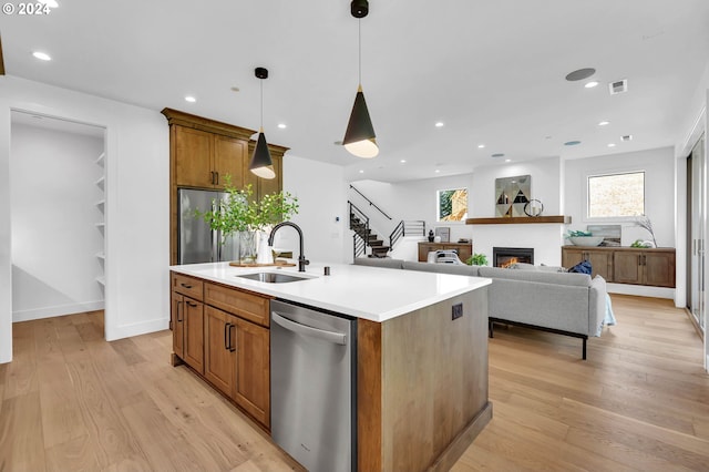 kitchen featuring a kitchen island with sink, appliances with stainless steel finishes, pendant lighting, and sink