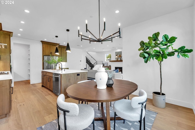 dining room with sink, a chandelier, and light hardwood / wood-style floors