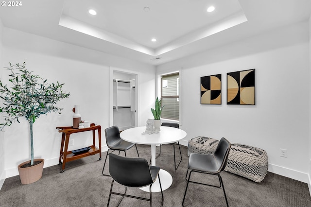 dining area with carpet floors and a tray ceiling