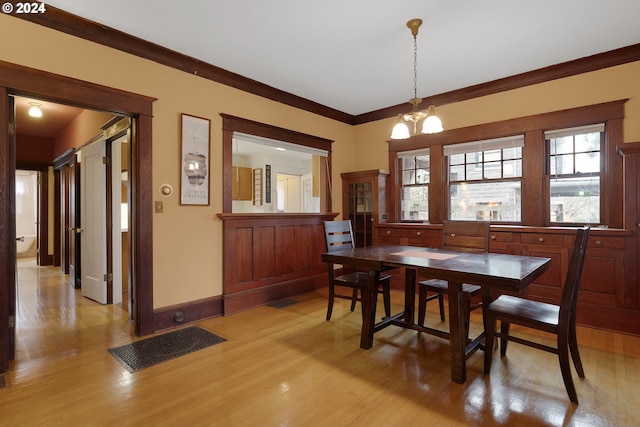 dining room featuring ornamental molding, a notable chandelier, and light wood-type flooring