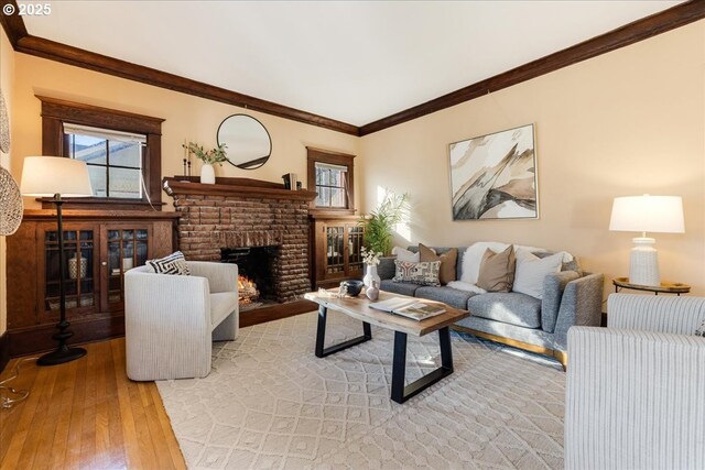 living room featuring a brick fireplace, crown molding, and light hardwood / wood-style floors