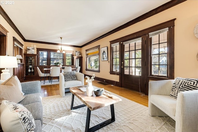 living room featuring crown molding, a chandelier, and light hardwood / wood-style floors