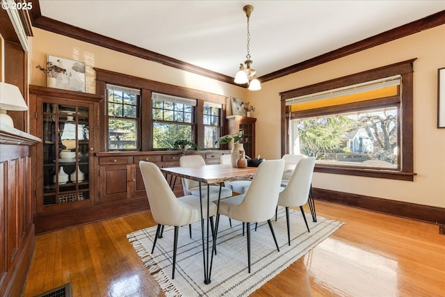 dining room with ornamental molding, plenty of natural light, and light wood-type flooring