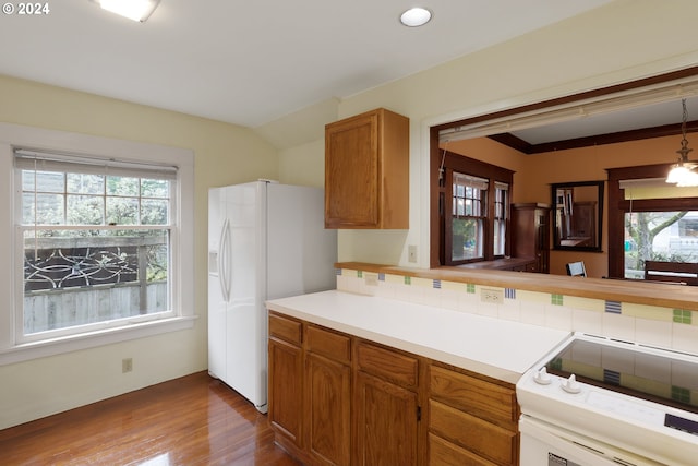 kitchen featuring hardwood / wood-style floors, decorative backsplash, white refrigerator with ice dispenser, range, and a notable chandelier