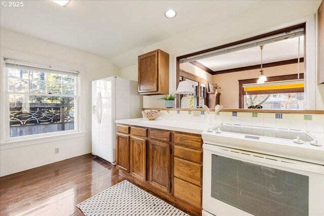 kitchen with white appliances, dark hardwood / wood-style flooring, and decorative light fixtures